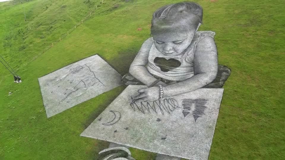 スイスの山に絵画をする2人の子供たちの地上絵、異なる高度から